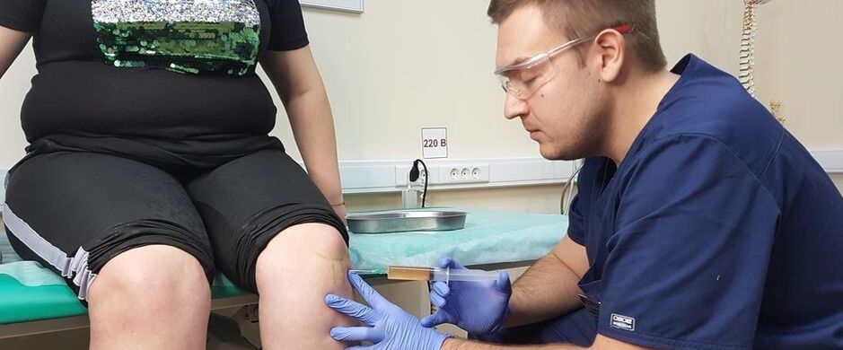 Um médico ortopedista faz uma injeção intra-articular na articulação do joelho para osteoartrite