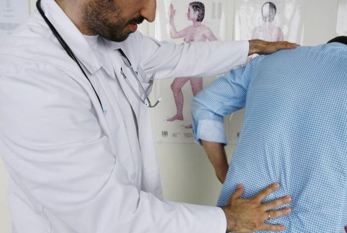 Médico examinando um paciente com dor nas costas na região lombar