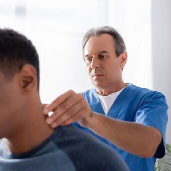 Um médico realiza um exame diagnóstico em um paciente com dor no pescoço.